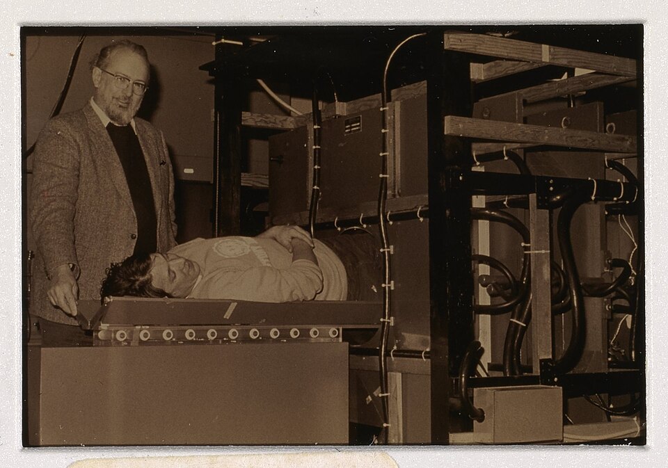 Paul Lauterbur beside an MRI machine